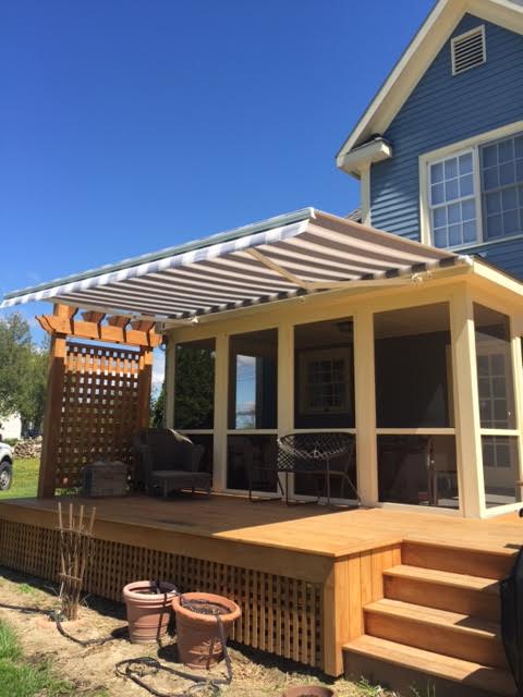 photo of a retractable awning over a deck in front of a screened porch providing shade on a sunny day